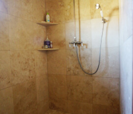 A large walk-in custom tile shower with travertine tile
